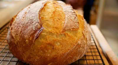A freshly baked loaf of bread resting on a cooling rack, showcasing its golden crust and inviting texture