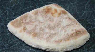 A piece of soda bread resting on a wooden table, showcasing its rustic texture and golden-brown crust